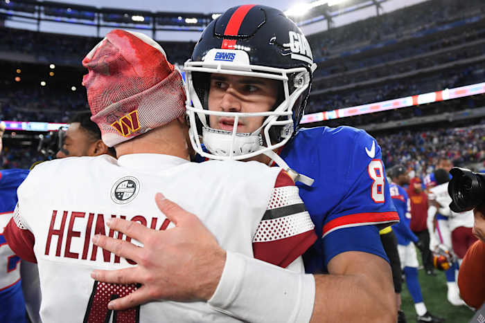Washington Commanders quarterback Taylor Heinicke and New York Giants quarterback Daniel Jones embrace on the field